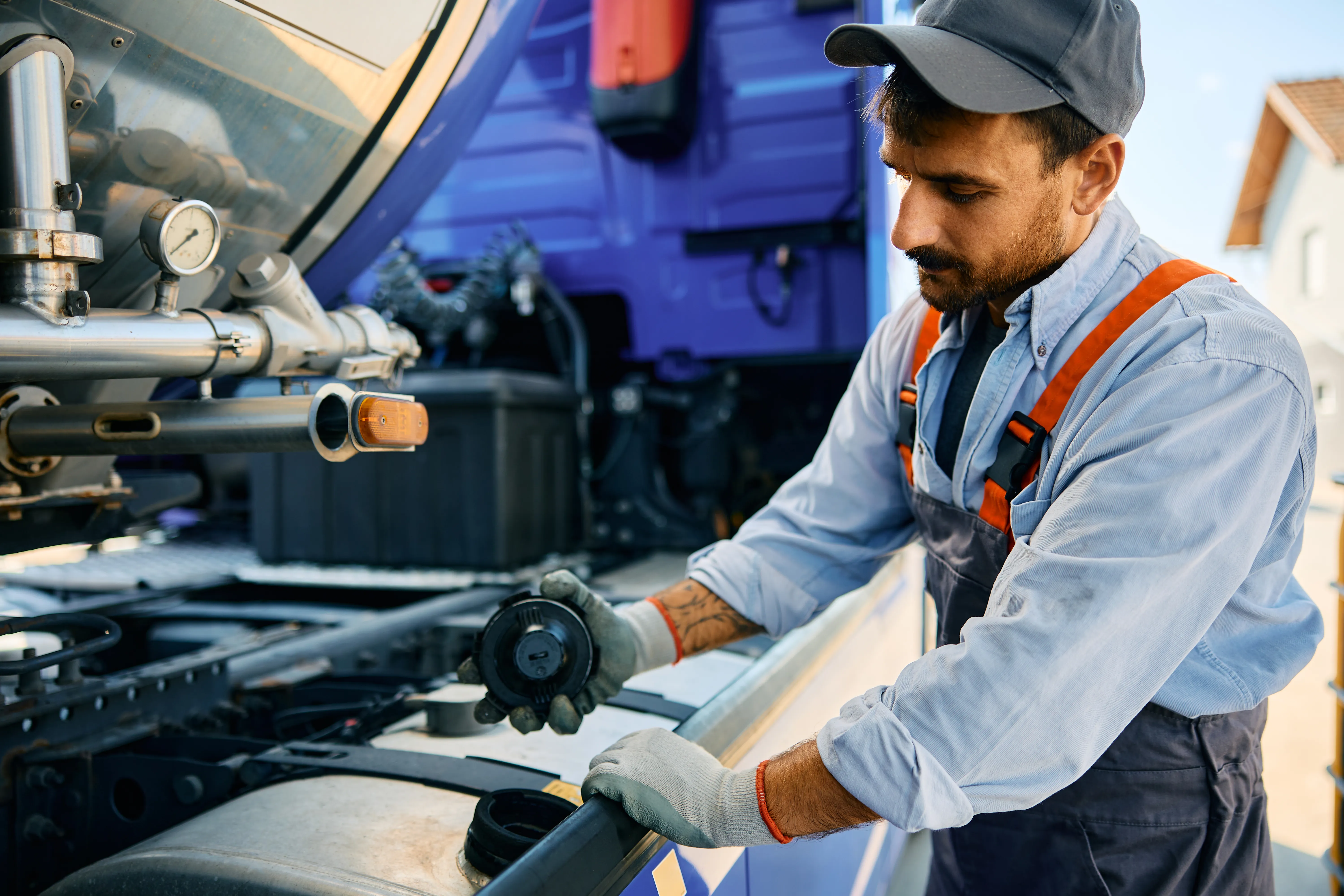 Un hombre que está revisando y llenando el tanque, hace un control de combustible